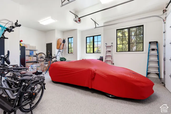 Spacious garage featuring a durable epoxy floor, multiple windows for natural light, overhead lighting, and an automatic garage door opener