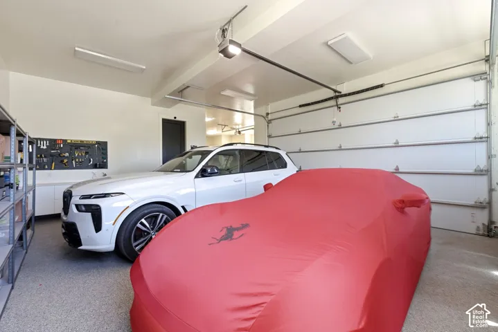 Spacious two-car garage featuring epoxy flooring, built-in storage shelving, overhead lighting, and white walls