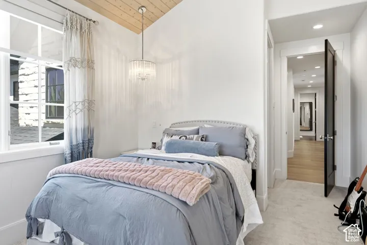 Bedroom featuring a vaulted wood-finish ceiling, an elegant chandelier, and a double-pane window