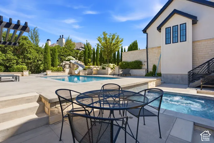 Expansive concrete patio area with a swimming pool and built-in spa