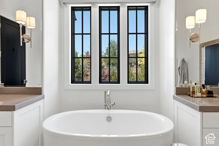 Freestanding soaking tub with a polished chrome deck-mounted faucet, framed by three vertical windows with black muntins