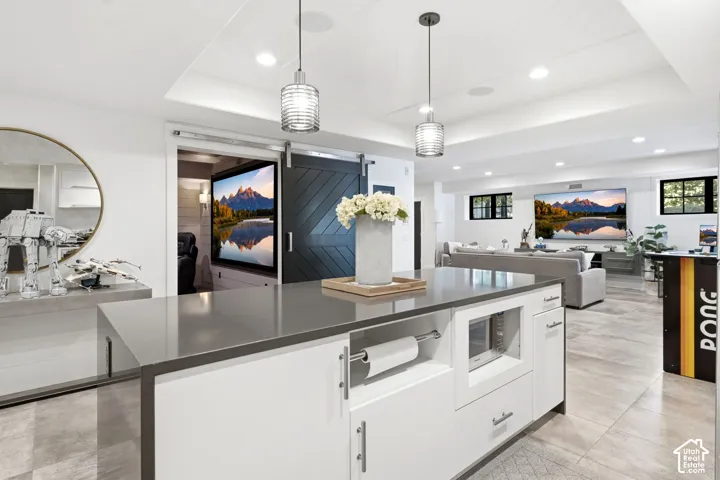 Spacious lower level featuring a central island with integrated microwave, pendant lighting, and a barn door entry