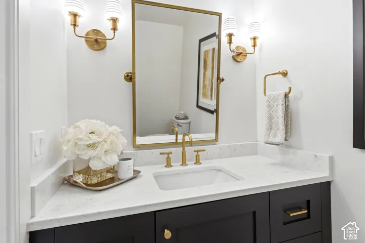 Vanity featuring a white undermount sink, brass faucet, and white countertop