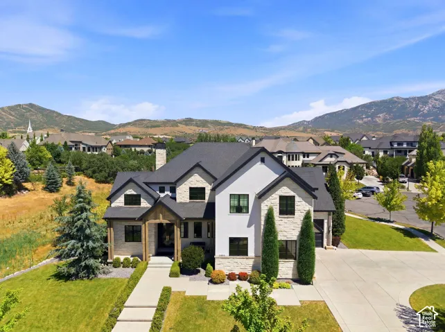 Modern stone and stucco exterior featuring a dark-pitched roofline and black-framed windows