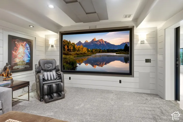 Expansive media room featuring a large projection screen, recessed lighting, wall-mounted sconces, and shiplap paneling