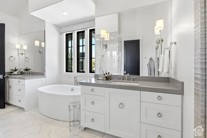 Contemporary bathroom featuring a freestanding oval tub, dual vanity with white shaker-style cabinetry, integrated rectangular sinks, and grey countertops