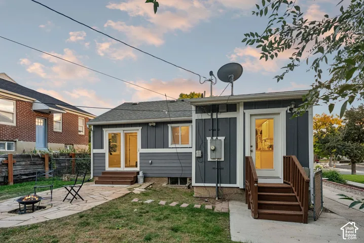 Modern cottage-style home featuring a charcoal exterior with yellow accent doors, elevated on a concrete foundation with wooden deck stairs