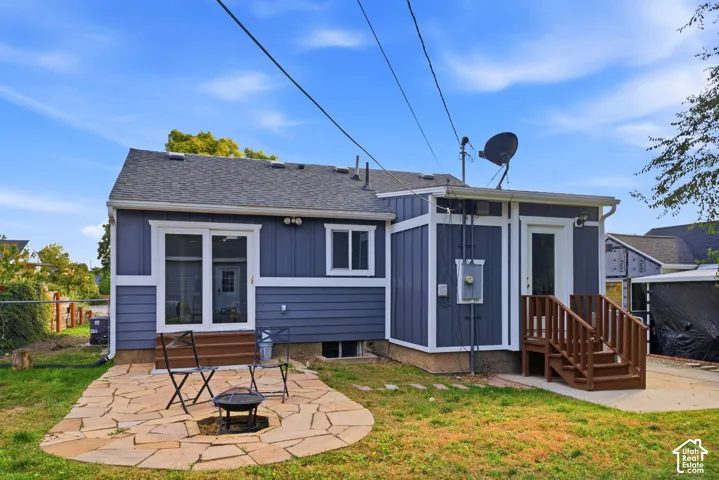 Rear exterior featuring gray siding, a flagstone patio, and a separate raised entrance with wood stairs