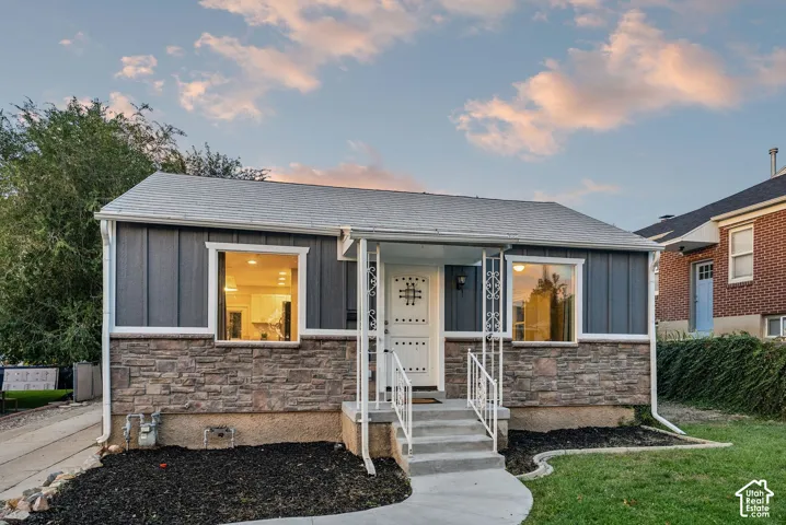 Exterior featuring stone veneer and vertical siding, a covered entry porch, and a concrete walkway
