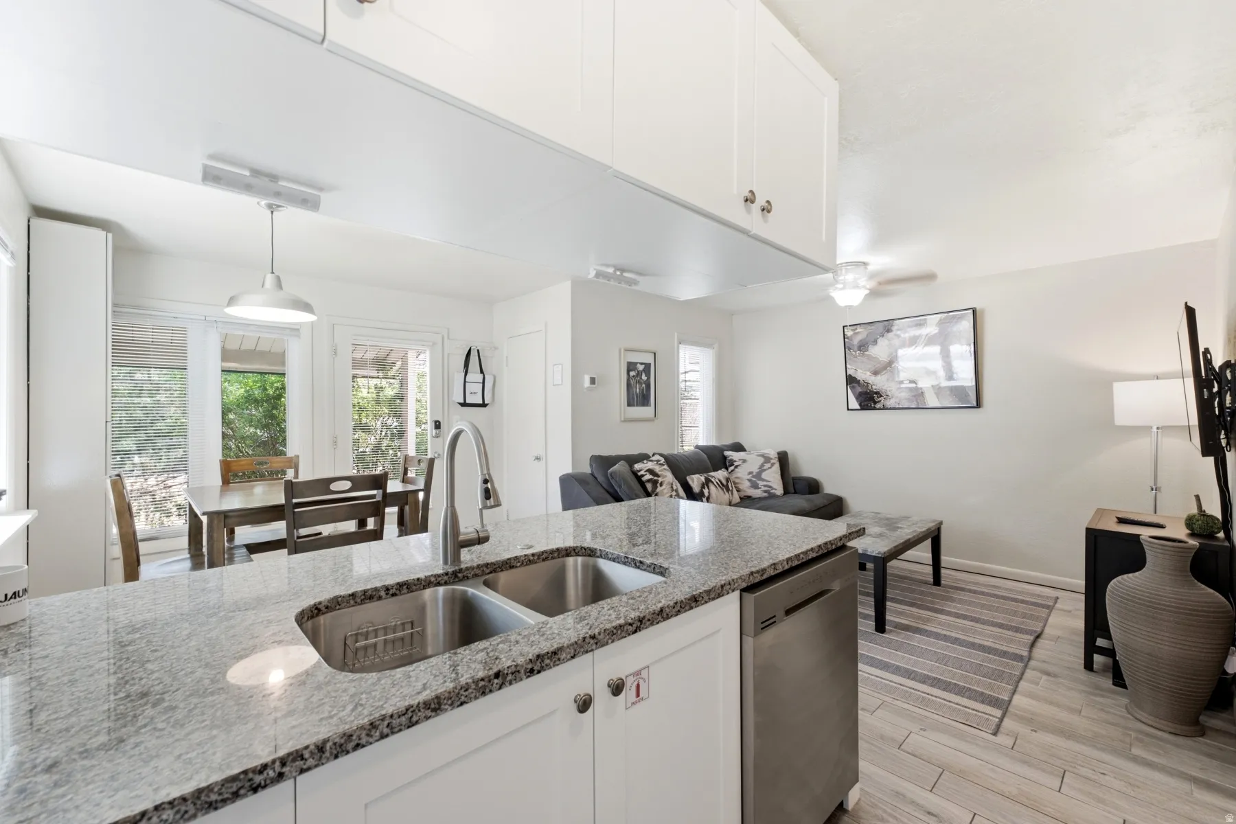 Kitchen island featuring a double basin stainless steel sink, a pull-down faucet, and light-toned stone countertops