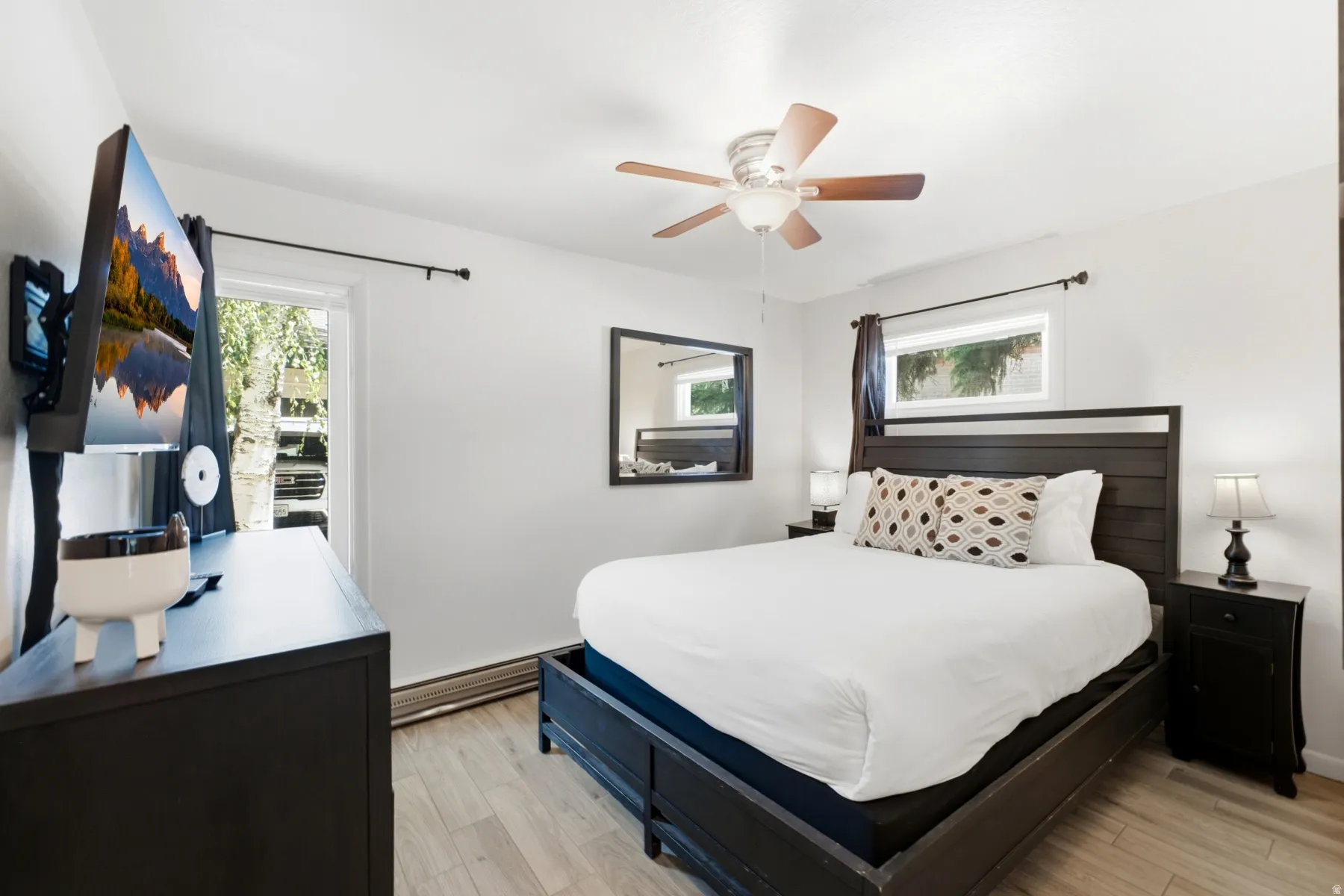 Bedroom featuring light wood-finish flooring, a contemporary ceiling fan, and white painted walls