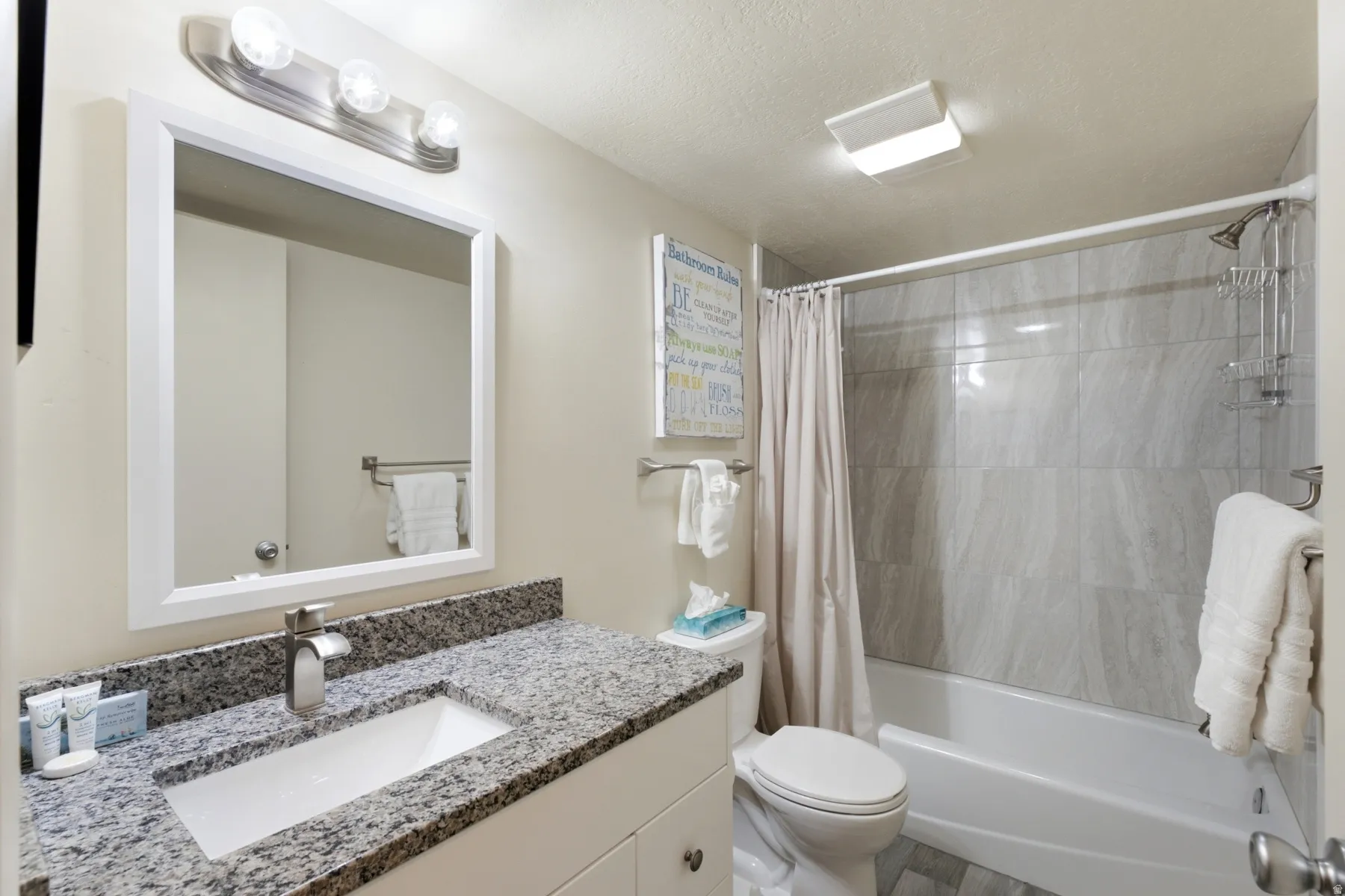 Bathroom featuring a single vanity with stone-finish countertop, undermount sink, and polished chrome faucet