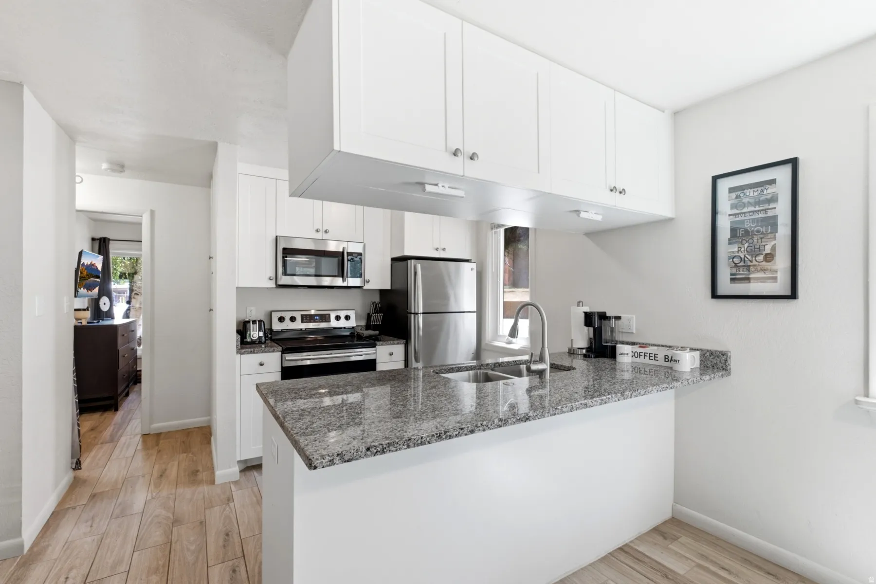 Kitchen featuring white shaker cabinetry, stainless steel appliances, speckled stone countertops, and a stainless steel sink with a gooseneck faucet