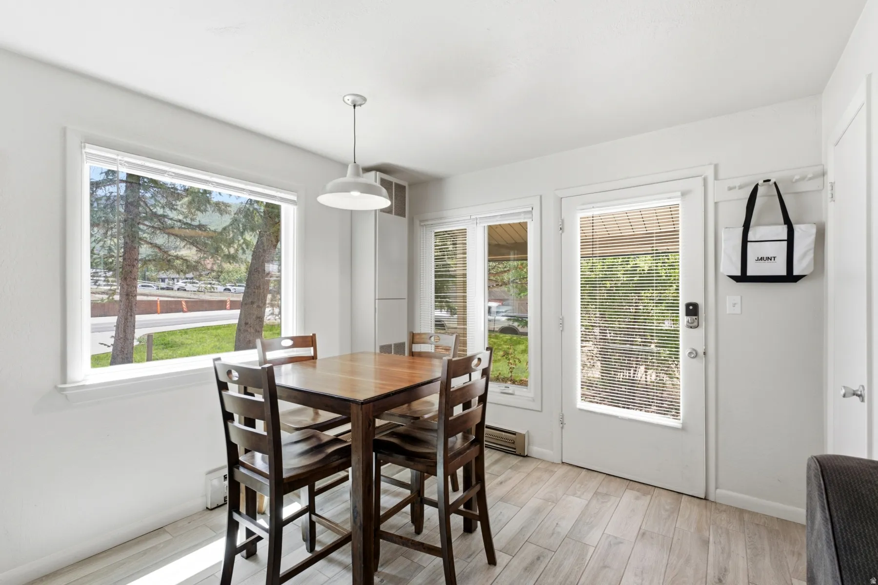 Dining area with light wood-finish flooring and a contemporary pendant light fixture