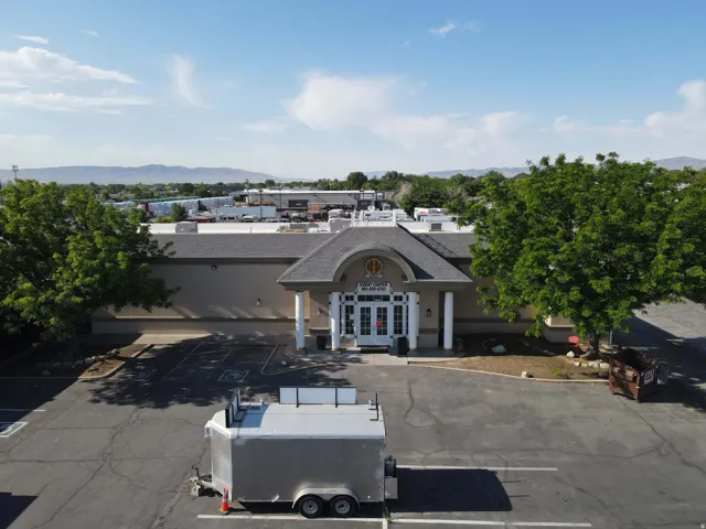 Commercial building with a prominent arched entry, multiple white pillars, and a dark shingled roof