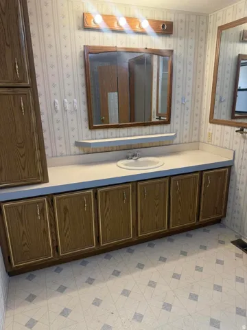 Bathroom featuring a wood-finish vanity with an integrated sink and light-toned countertop
