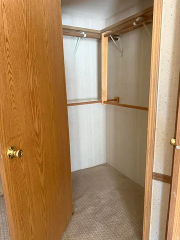 Interior closet featuring wood-finish shelving and hanging rods