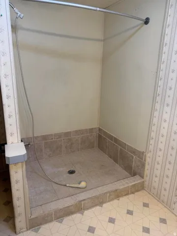 Walk-in shower featuring a handheld spray, tiled base, and coordinating tiled surround