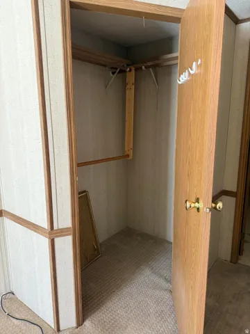 Carpeted closet interior featuring wood-finish framing and shelving