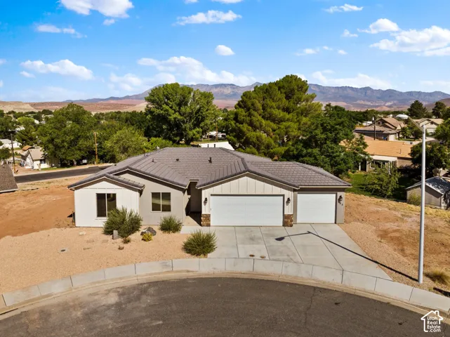 Modern ranch-style home featuring a two-car garage, light-toned exterior siding, and a contrasting dark tile roof
