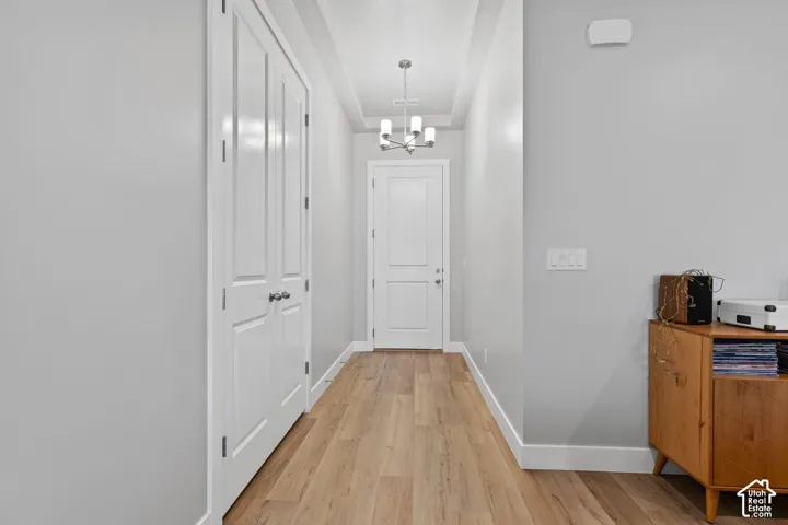 Entryway featuring wood-finish flooring, light gray walls, white trim, and a modern chandelier