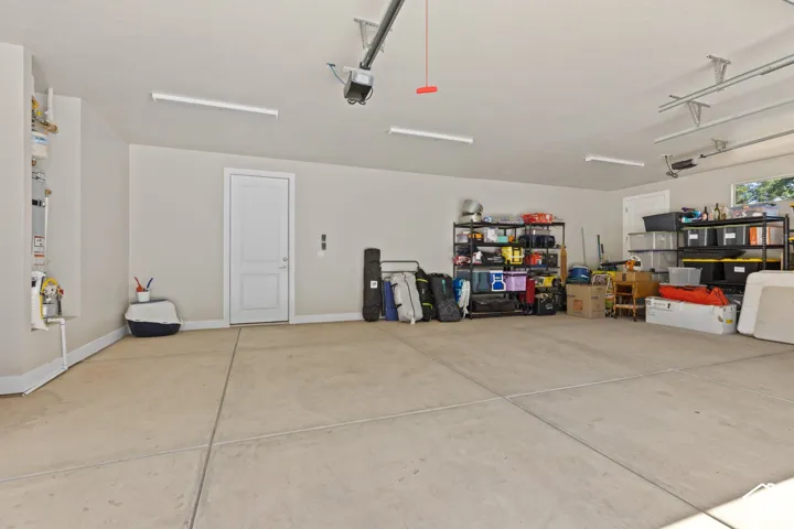 Spacious garage featuring a concrete floor, painted walls, overhead fluorescent lighting, and a window for natural light
