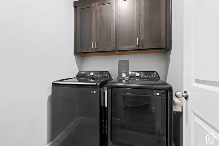 Laundry area featuring dark wood-finish cabinetry with silver hardware