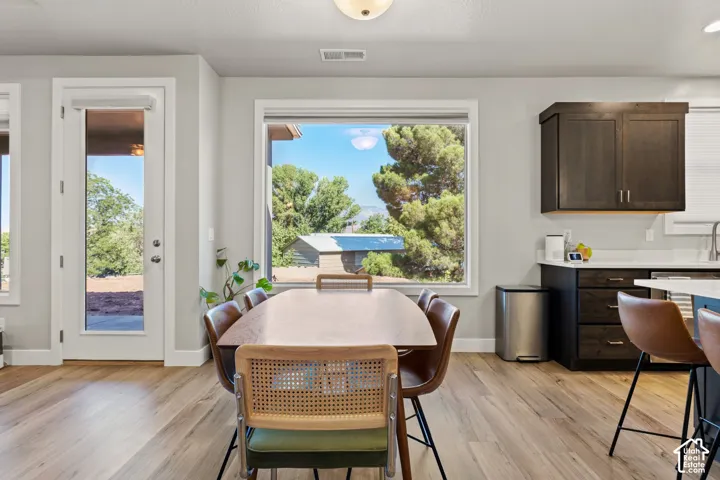 Spacious dining area featuring wood-finish flooring, a large picture window, and direct exterior access via a glass-paneled door