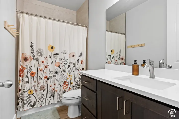 Bathroom featuring a dark wood-finish vanity with a white solid-surface countertop and integrated sink, a large wall-mounted mirror, and a tub/shower combination with light-toned tiled surrounds