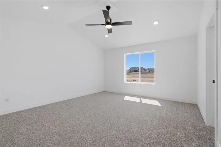 Vaulted ceiling with a ceiling fan, recessed lighting, double-pane window, and neutral carpeting