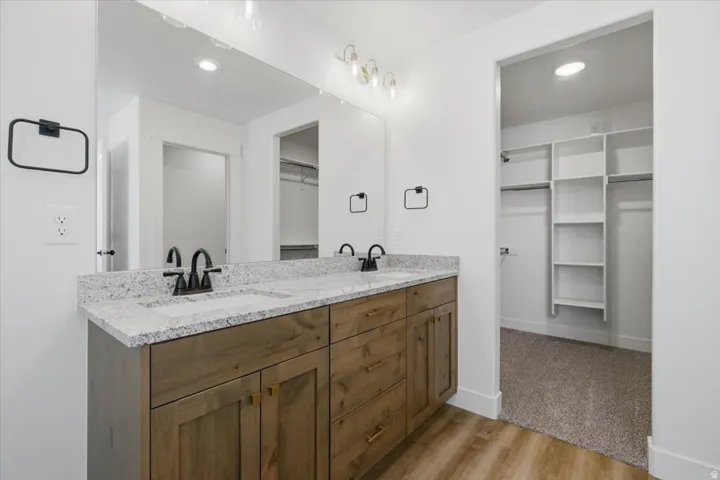 Double vanity with a granite countertop, wood-finish cabinetry, and black hardware