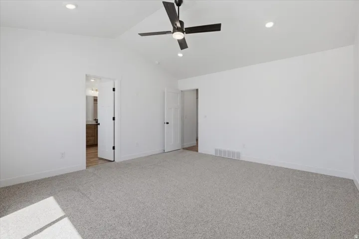 Spacious room featuring vaulted ceilings, recessed lighting, a ceiling fan, and light-toned carpeting