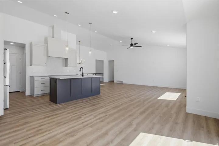 Open-concept living space with vaulted ceilings, recessed lighting, and wood-finish flooring