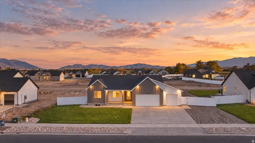 Contemporary exterior with dark siding and white trim, covered entry, attached two-car garage, concrete driveway, and a fenced yard