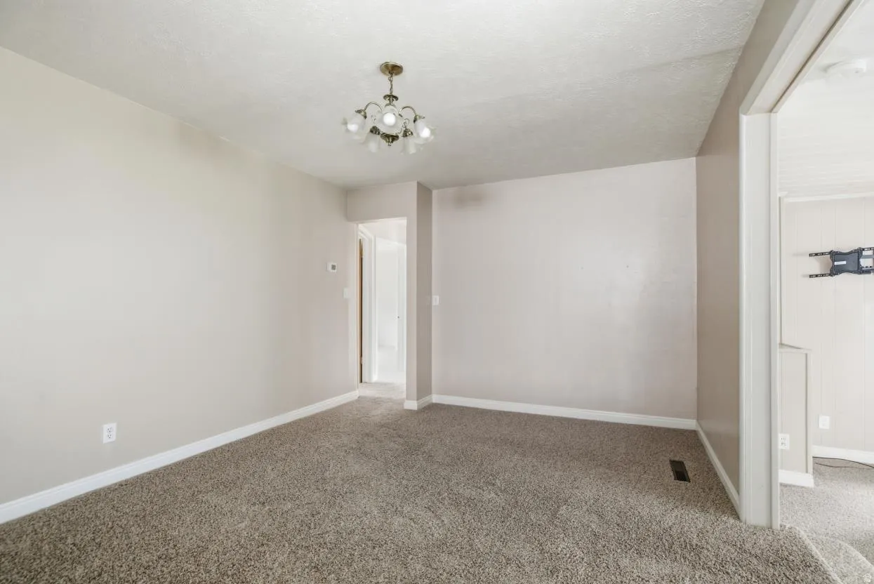 Carpeted interior space featuring a brass-finish chandelier and light-toned wall paint