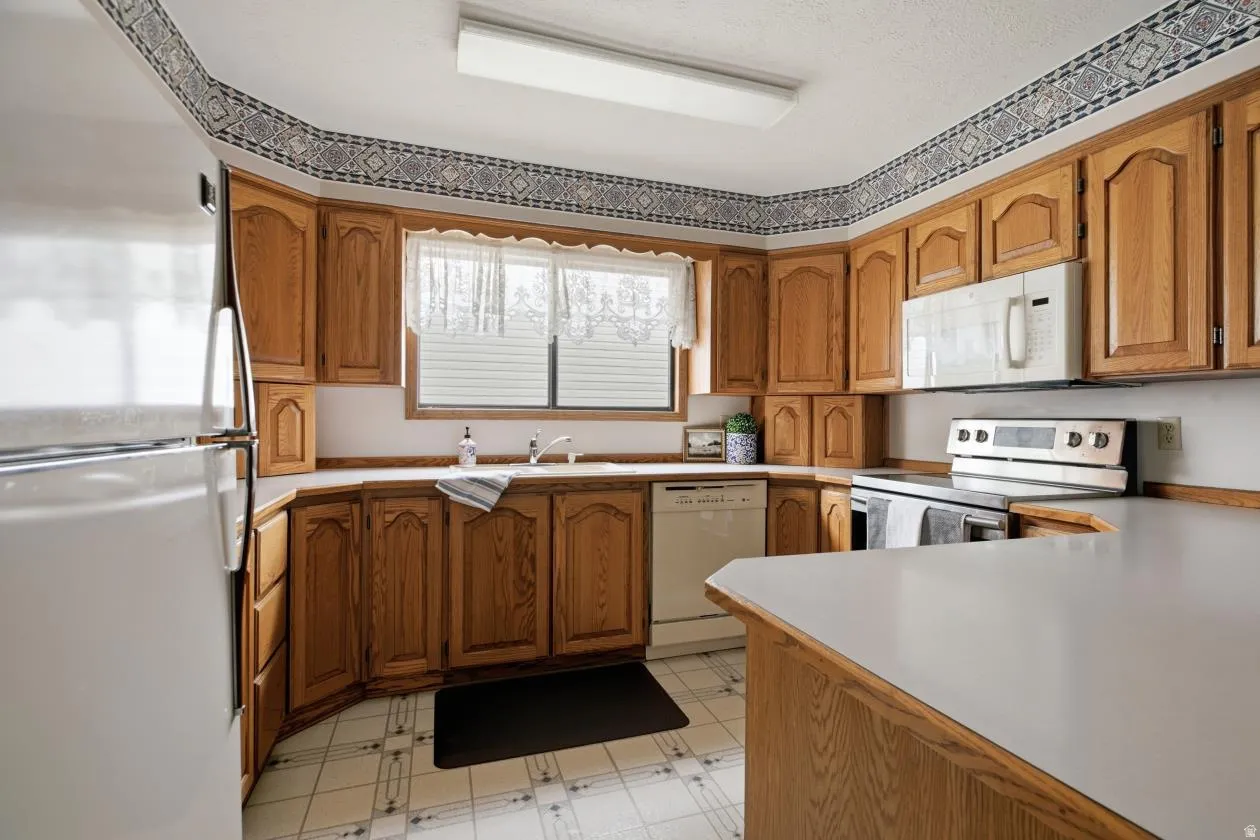 Kitchen featuring wood-finish cabinetry, white countertops, and a window above the sink