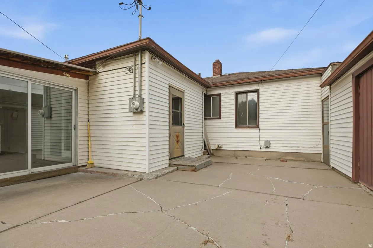 Concrete patio area featuring white siding and brown trim