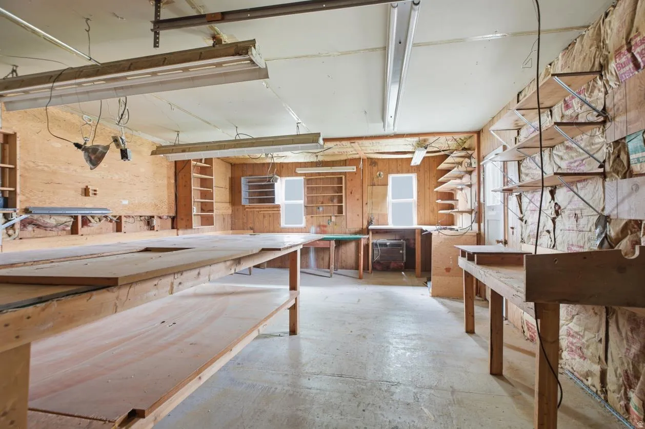 Workshop space featuring multiple built-in shelving units and broad workbenches