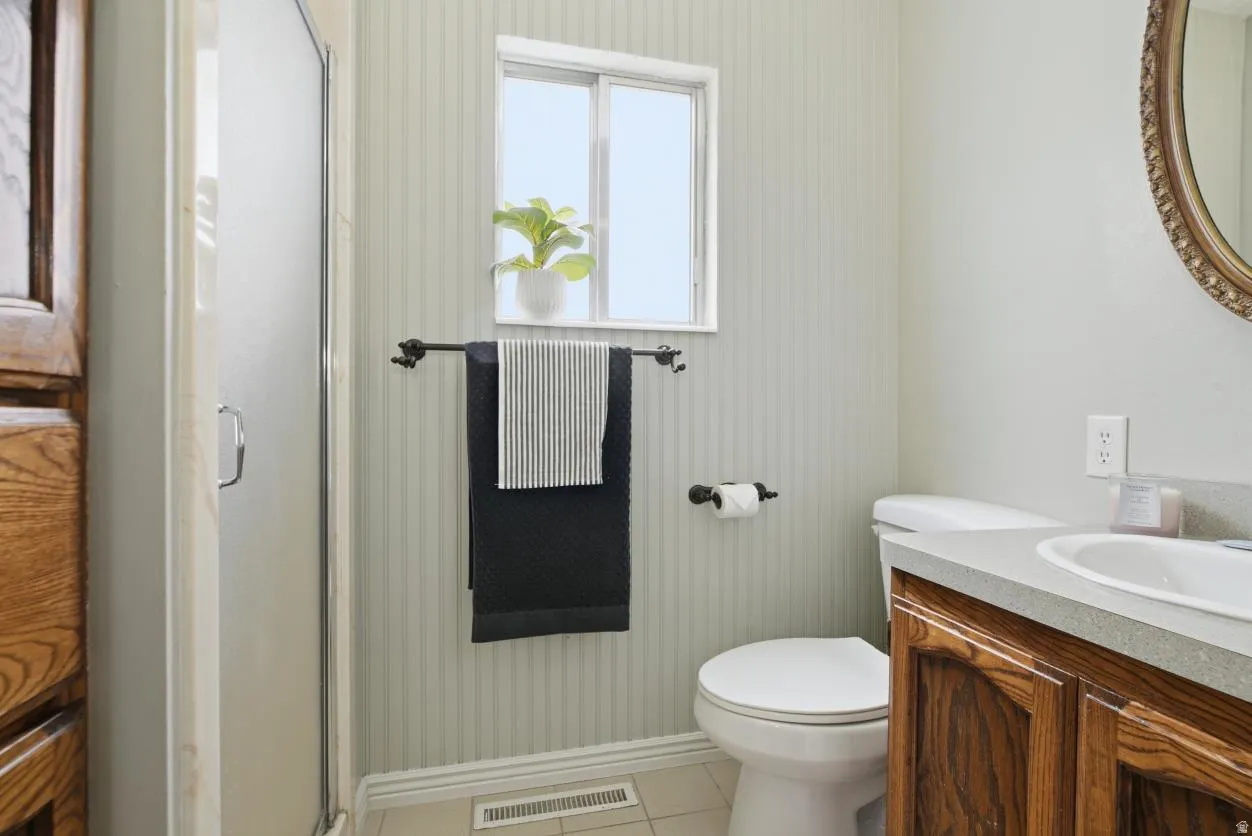 Bathroom featuring a shower with frosted glass enclosure, a toilet, and a vanity with wood-finish cabinetry and an integrated sink