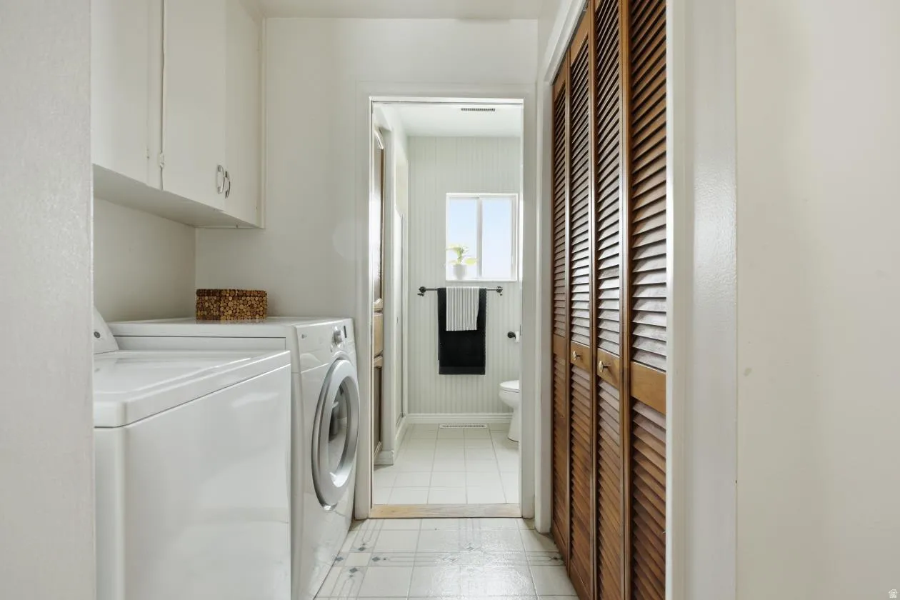 Laundry area featuring white cabinetry, a built-in counter, and louvered wood doors