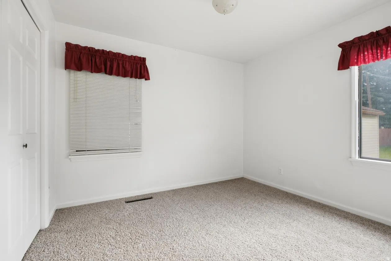Bright room featuring a neutral carpet, white walls, and a white six-panel door