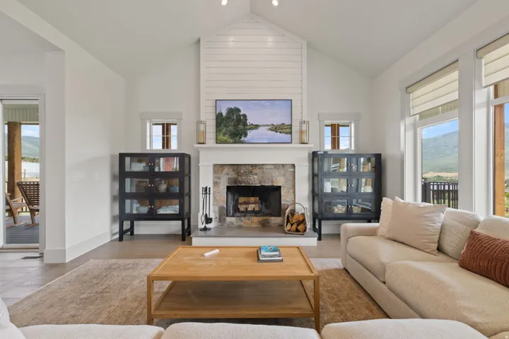 Living area featuring a stone fireplace with a wood mantel, shiplap accent wall, and vaulted ceiling