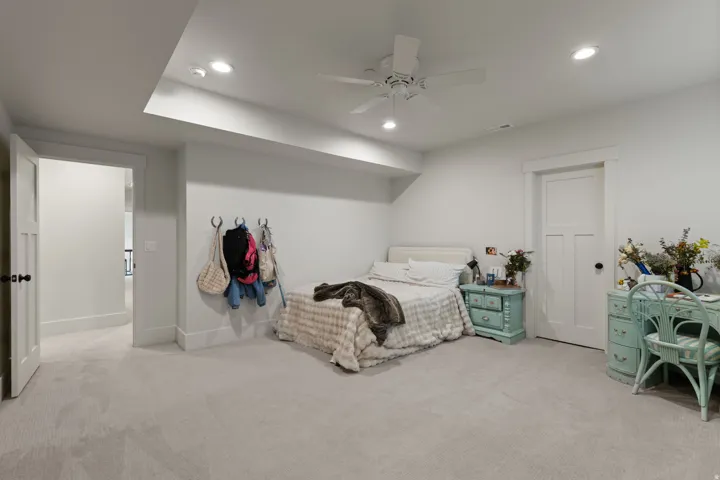 Carpeted room featuring recessed lighting, a ceiling fan, a white paneled door, and a built-in wall rack