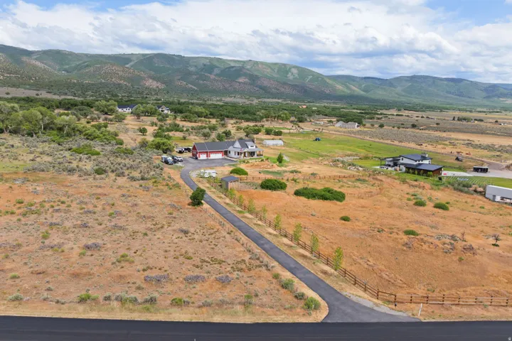 Expansive property featuring a paved driveway, fencing, and distant mountain scenery