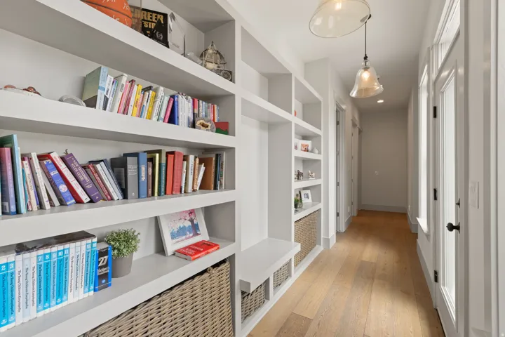 Built-in white shelving with integrated bench seating, natural wood-finish flooring, and recessed lighting