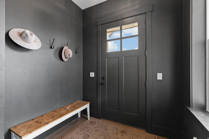 Entryway featuring a dark paneled door with glass inserts, complementing dark walls, and wood-finish flooring