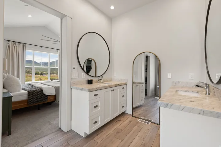 Dual vanity bathroom featuring light-toned wood-finish flooring