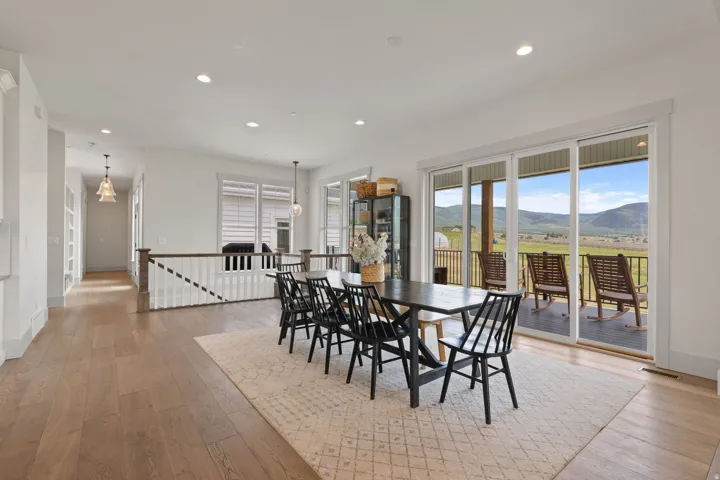 Spacious dining area featuring wood-finish flooring, recessed lighting, and a white baluster railing