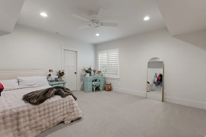 Spacious room featuring light gray carpeting, recessed lighting, white ceiling fan, horizontal window blinds, and white trim work