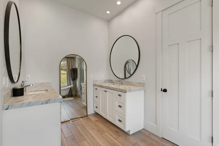 Dual vanities featuring stone countertops and round black-framed mirrors